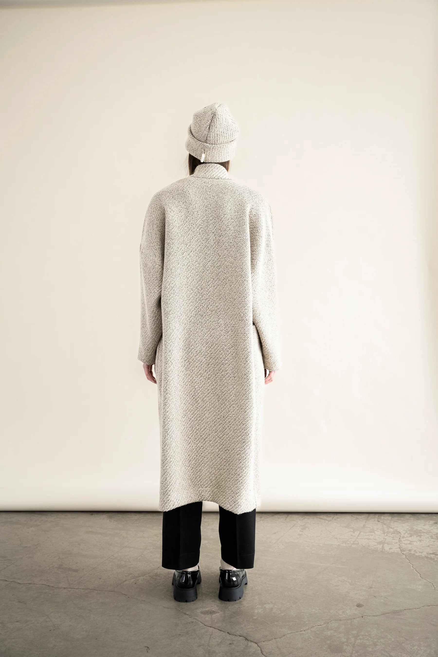 Back view of BodyBag by Jude long textured cream beige knit cardigan with matching beanie and black pants in Kelowna