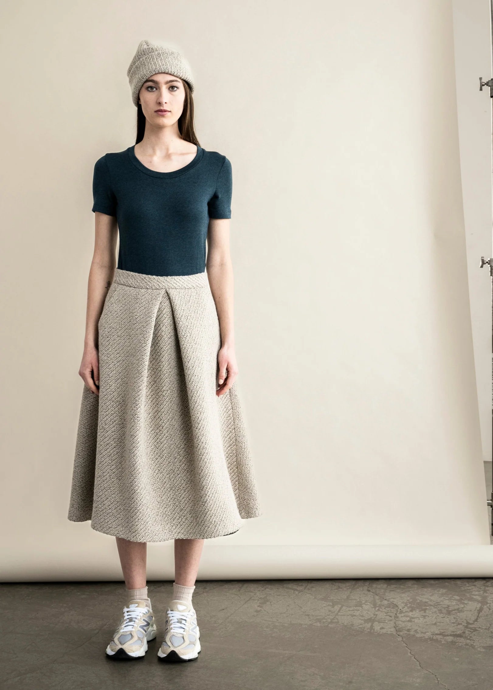Bodybag by Jude model wearing a fitted green t-shirt paired with a stylish pleated skirt for a chic look in Kelwona