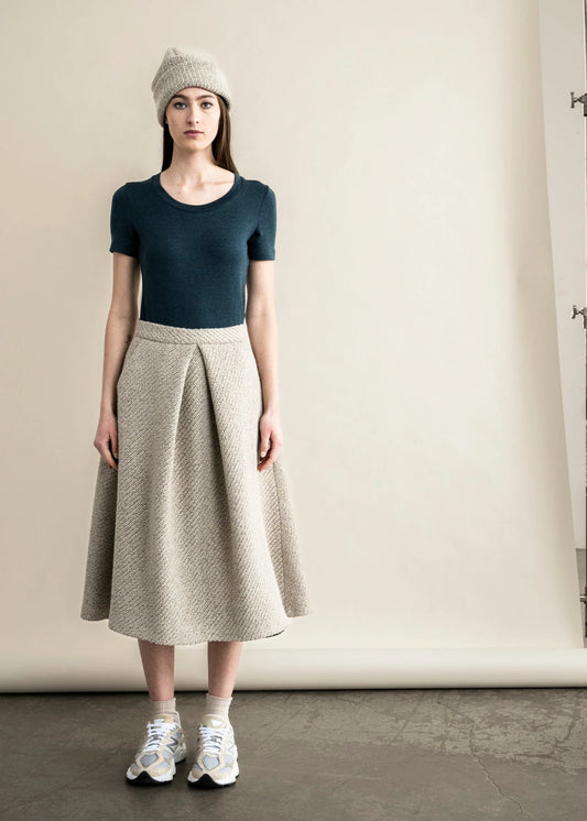 Bodybag by Jude model wearing a fitted green t-shirt paired with a stylish pleated skirt for a chic look in Kelwona