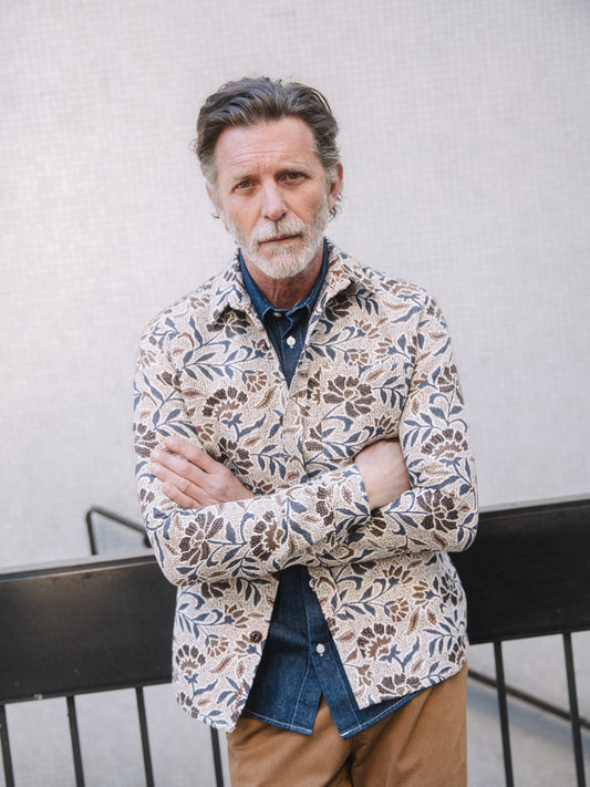 Older man wearing organic men's overshirt with floral print over denim shirt, arms crossed, casual look in Kelowna