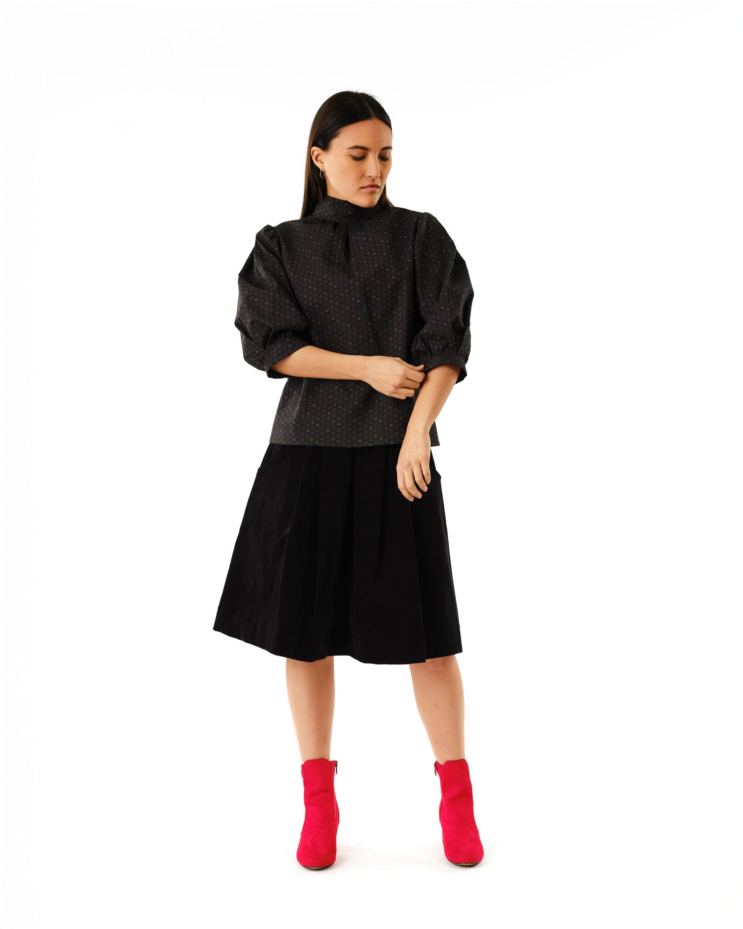 Jennifer Glasgow Design black textured high neck blouse and pleated skirt with fuchsia ankle boots in Kelowna