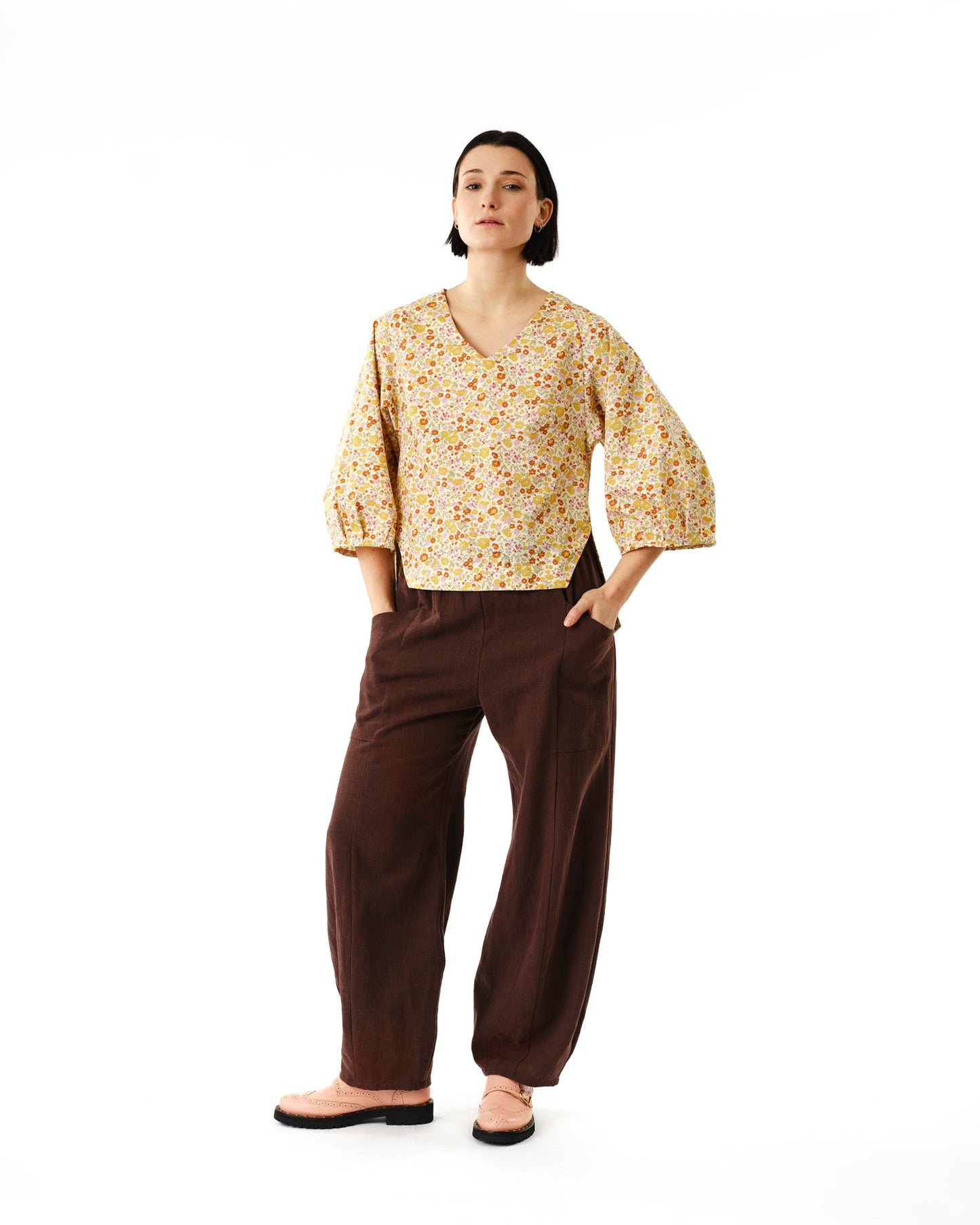 Jennifer Glasgow Design woman wearing yellow floral V neck blouse with puff sleeves and brown wide leg pants in Kelowna