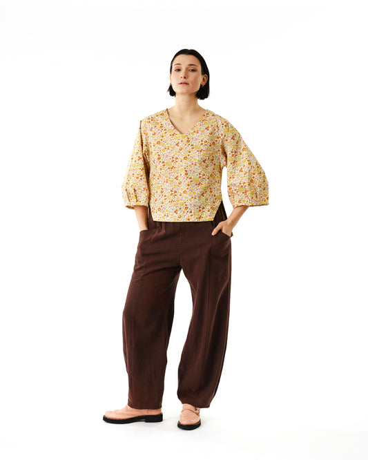Jennifer Glasgow Design woman wearing yellow floral V neck blouse with puff sleeves and brown wide leg pants in Kelowna
