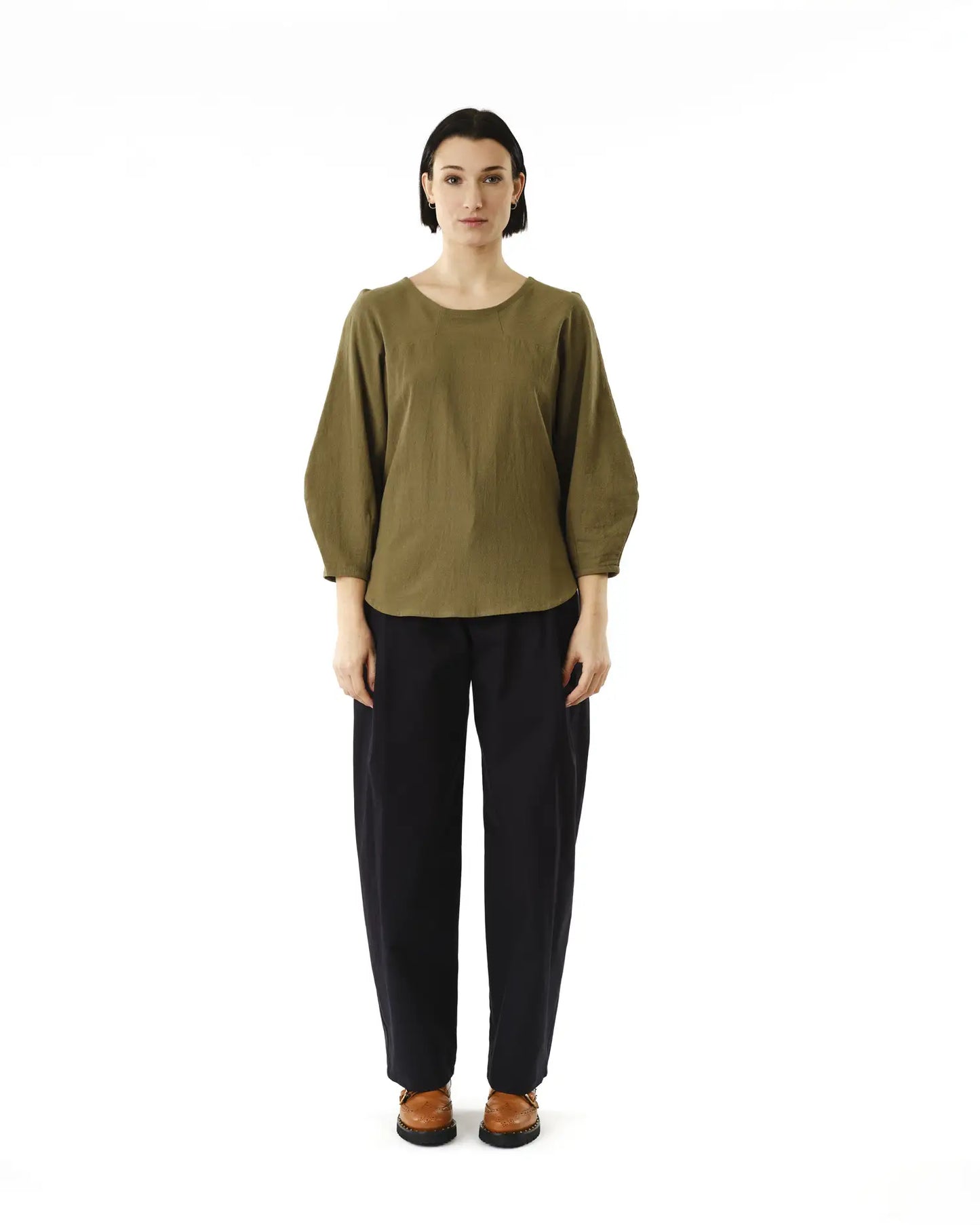 Jennifer Glasgow Design model wearing olive green three quarter sleeve puff blouse with round neck and black trousers in Kelowna