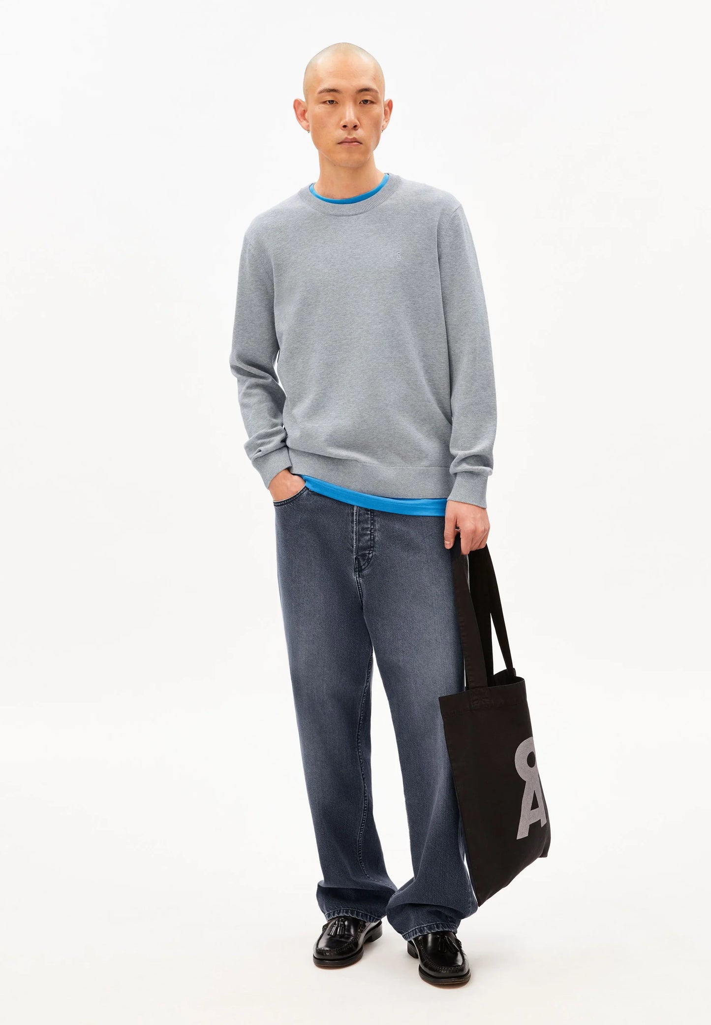 Men's ARMEDANGELS Canada  light gray sweater with blue neckline, styled with loose jeans and a black tote bag