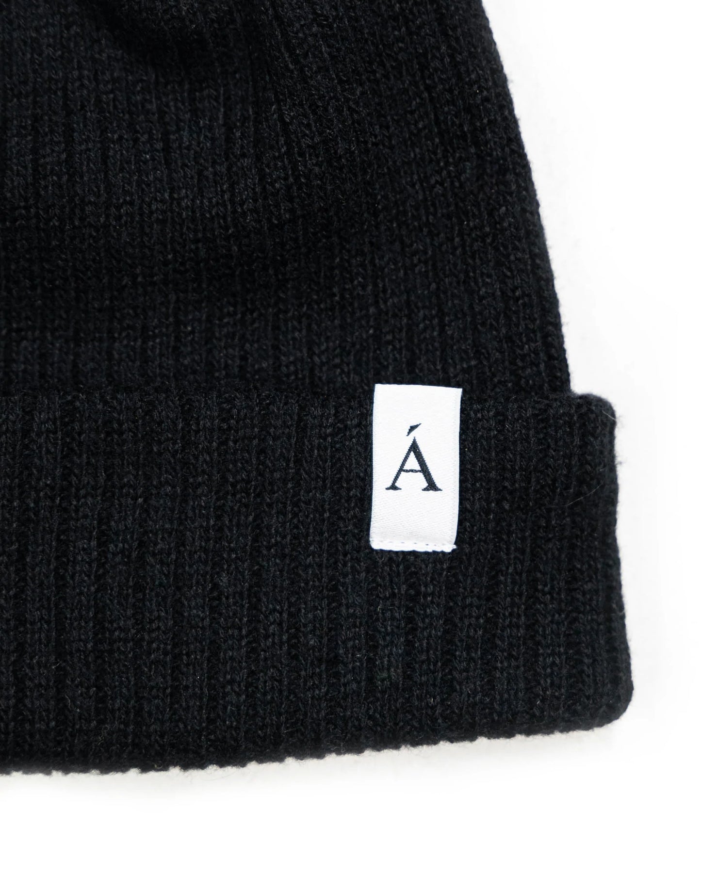 Black ribbed knit beanie with folded cuff and white logo tag for cold weather style and warmth in Kelowna