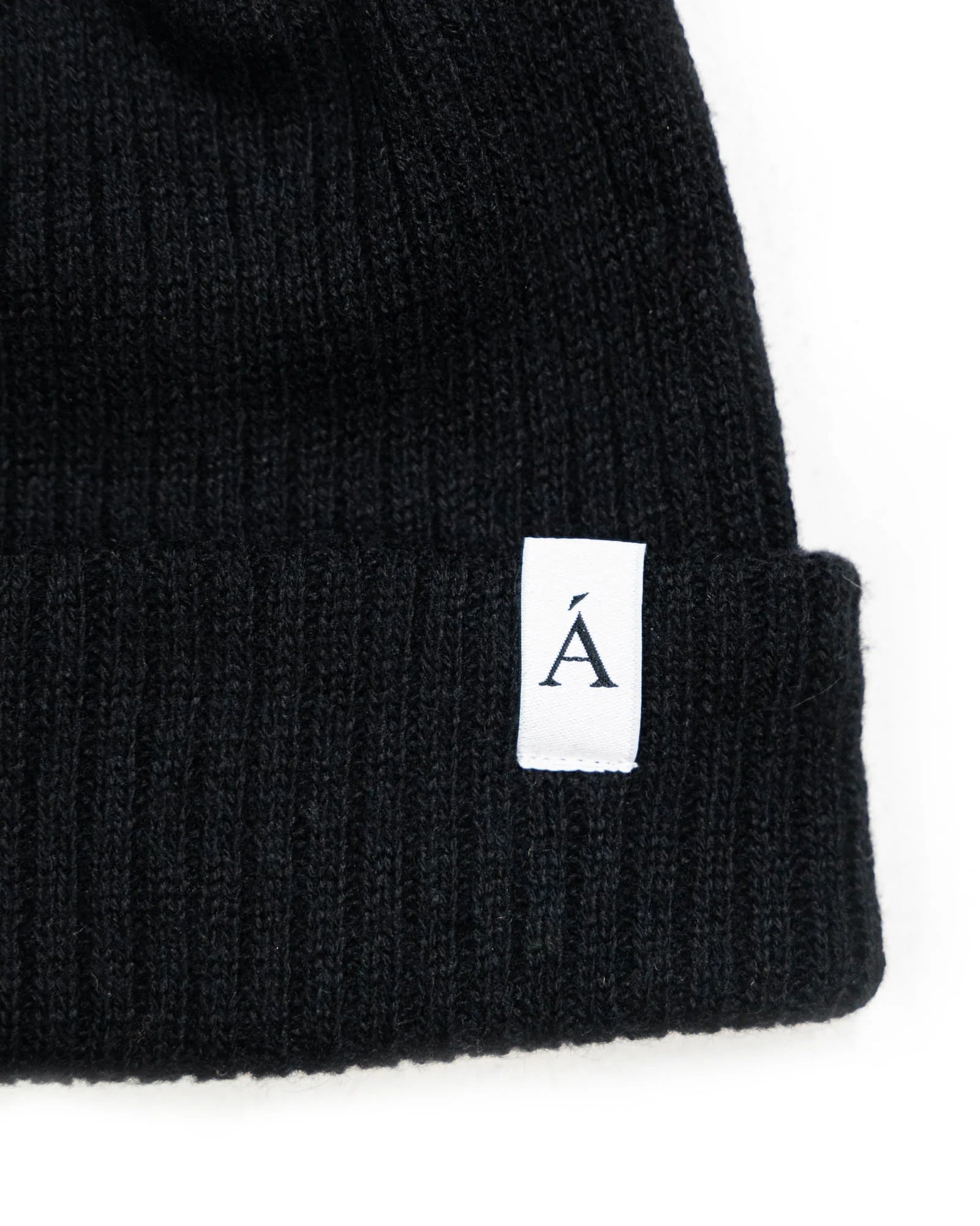 Black ribbed knit beanie with folded cuff and white logo tag for cold weather style and warmth in Kelowna
