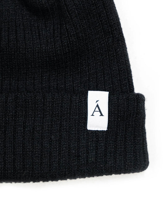 Black ribbed knit beanie with folded cuff and white logo tag for cold weather style and warmth in Kelowna
